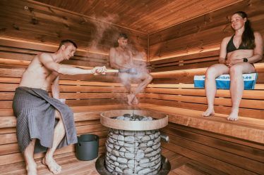 Three people enjoying a steamy sauna session, embracing wellness and relaxation.